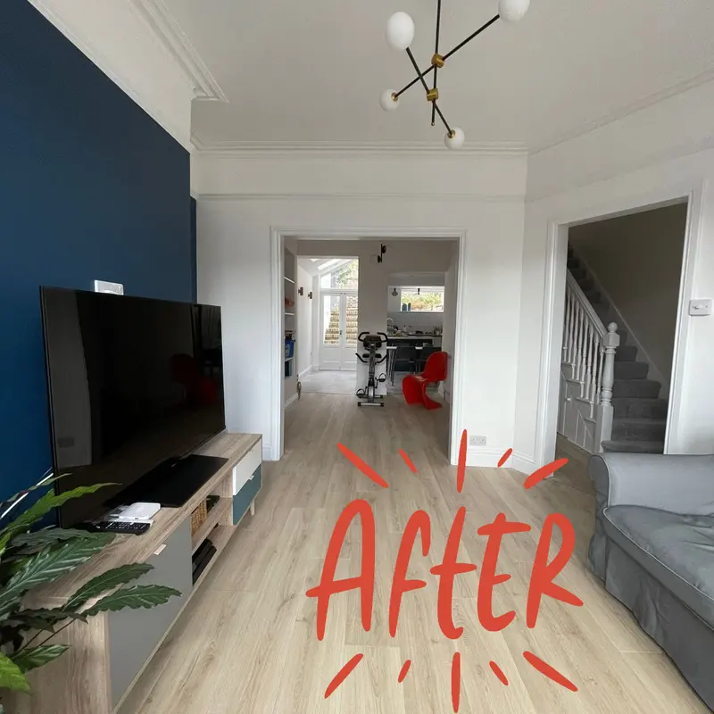 Finished living room with a navy feature wall and new laminate flooring
